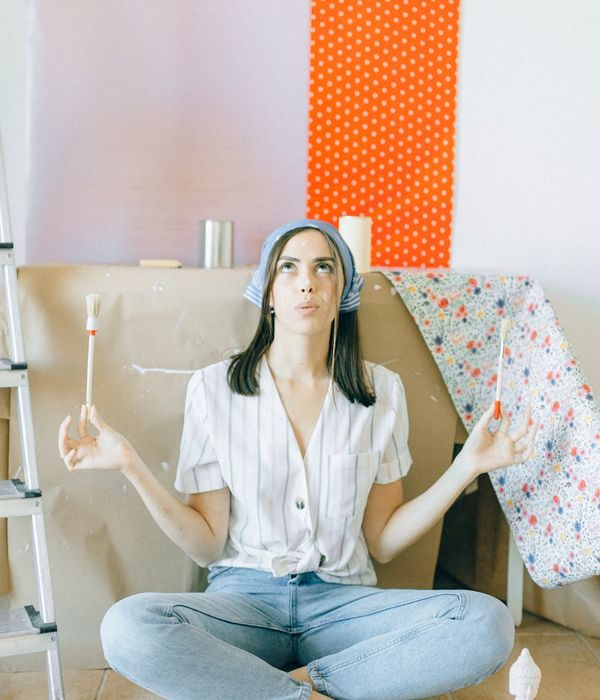 Woman in a calming yoga pose against a pistachio-colored background.